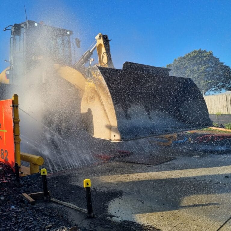 Truck wheel washers from NES Hire, washing a front end loader as it leaves the work site.