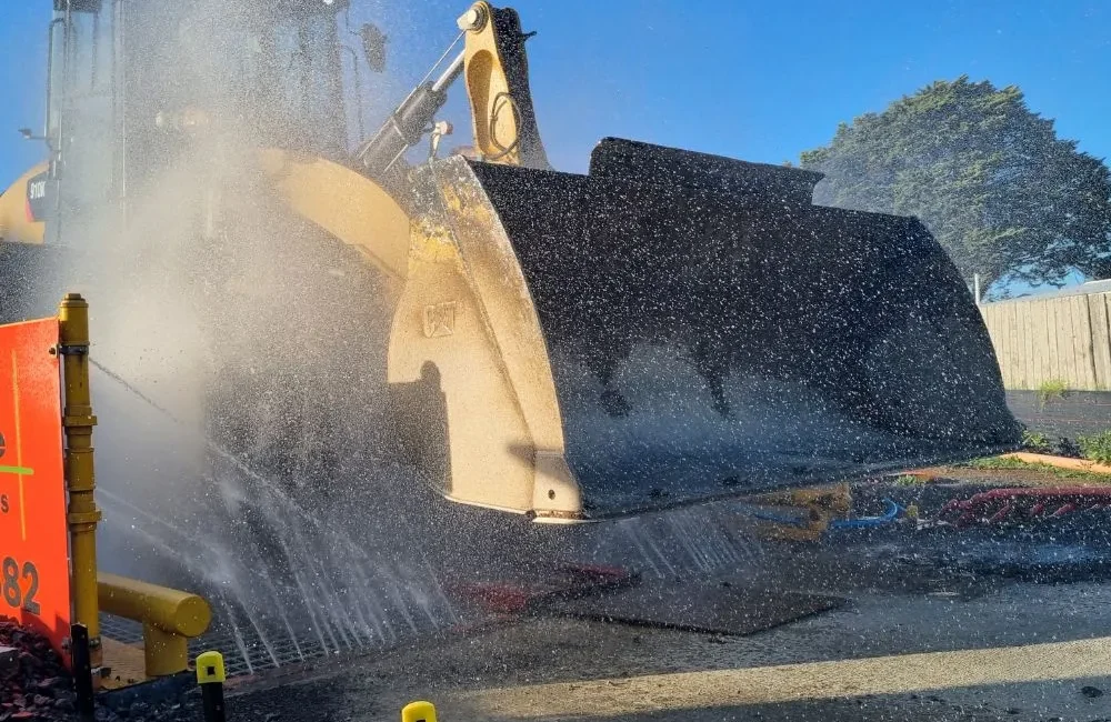 Truck wheel washers from NES Hire, washing a front end loader as it leaves the work site meeting code comliance.